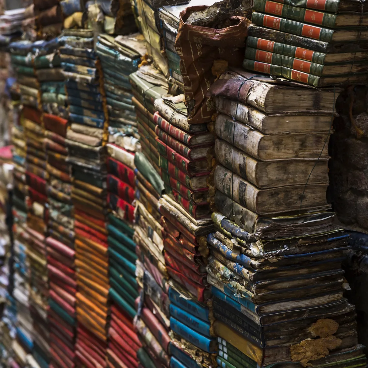 Viele alte, verwitterte Bücher sind hoch gestapelt.