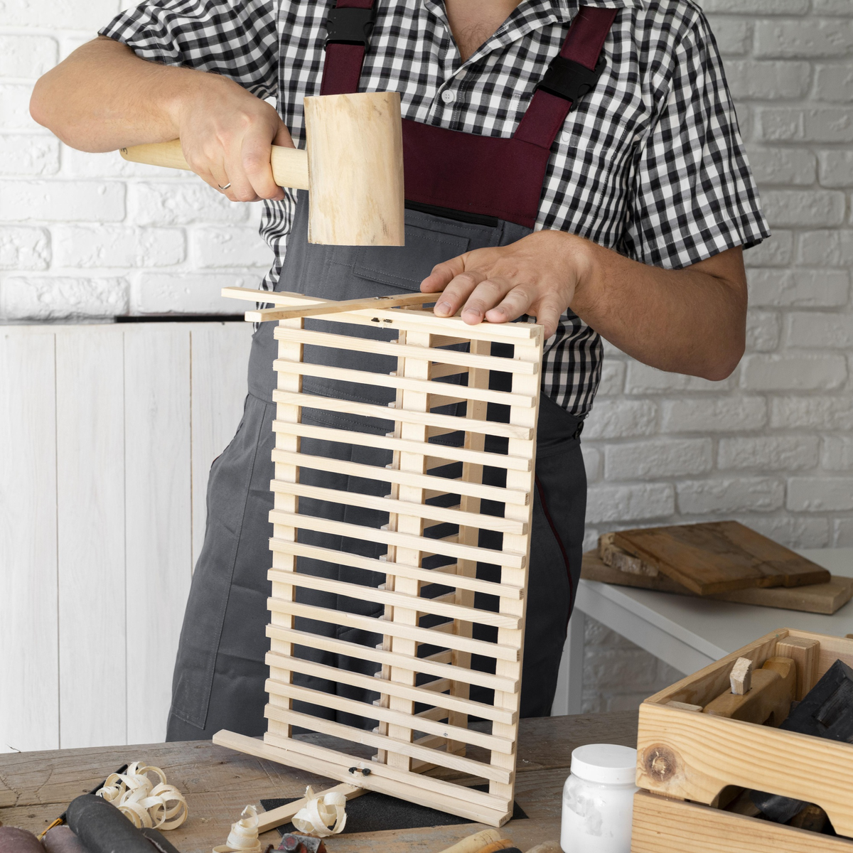 Ein Handwerker baut ein Holzgestell mit einem Holzhammer.