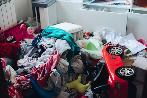 Unordentliches Kinderzimmer mit Kleidungsberg und Spielzeug.