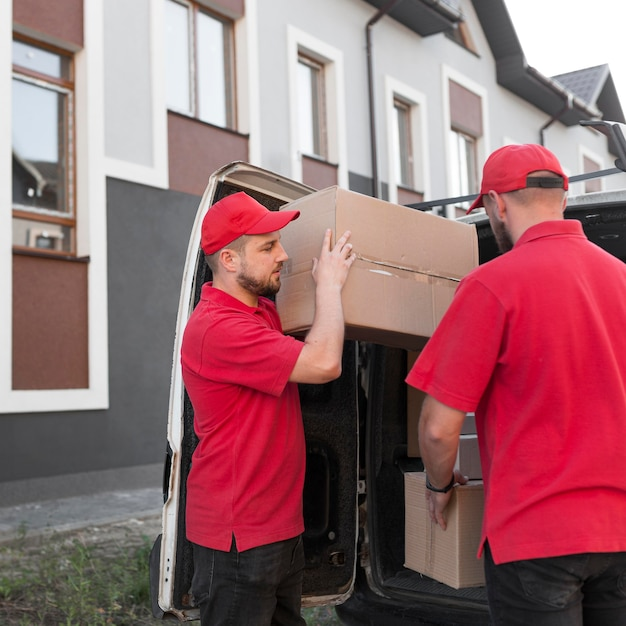 Zwei Liefermänner in Rot laden Kartons aus Transporter.