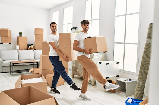 Zwei Männer tragen Umzugskartons in heller Wohnung.