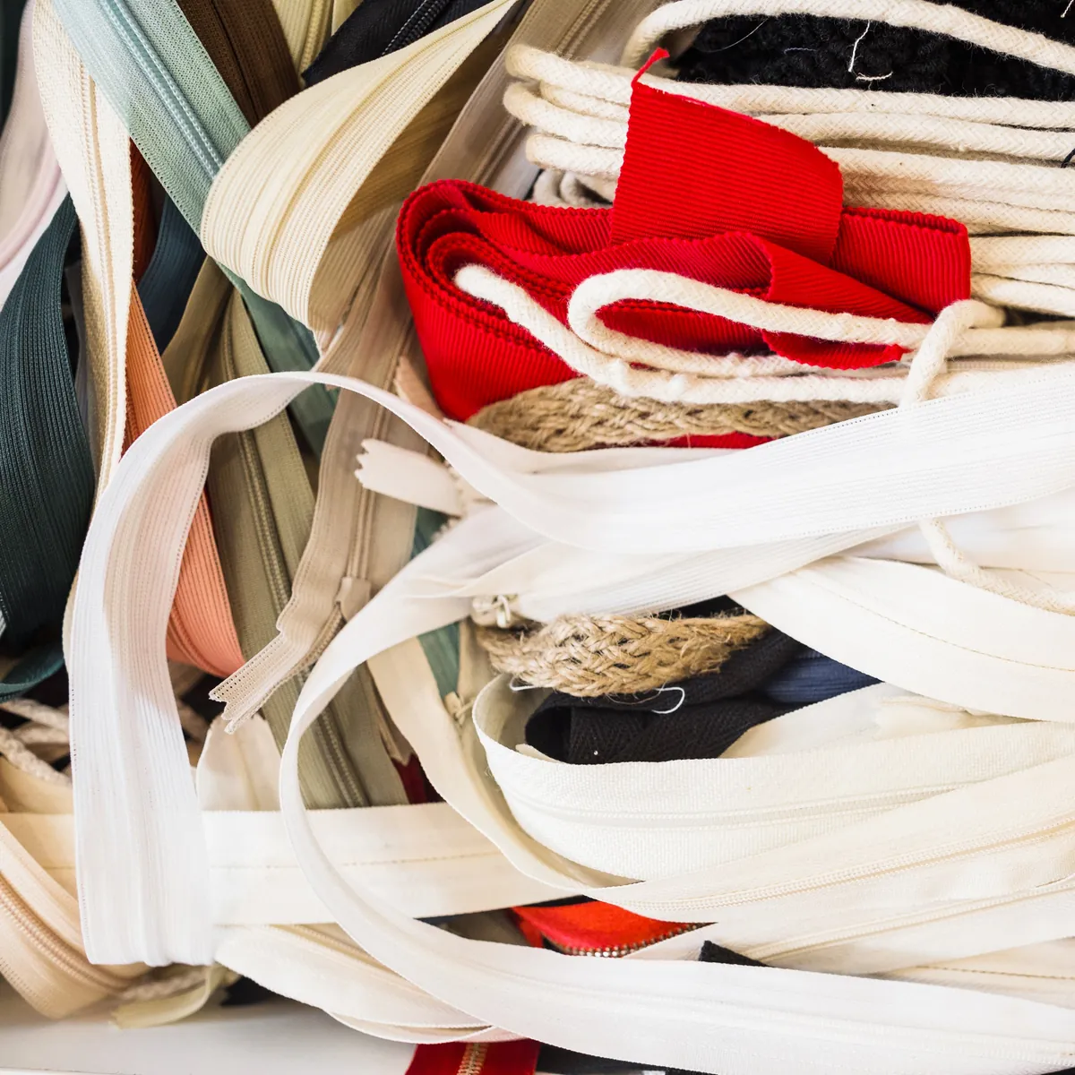 Bunte Nähzubehör-Sammlung mit Reißverschlüssen, Bändern und Kordeln.