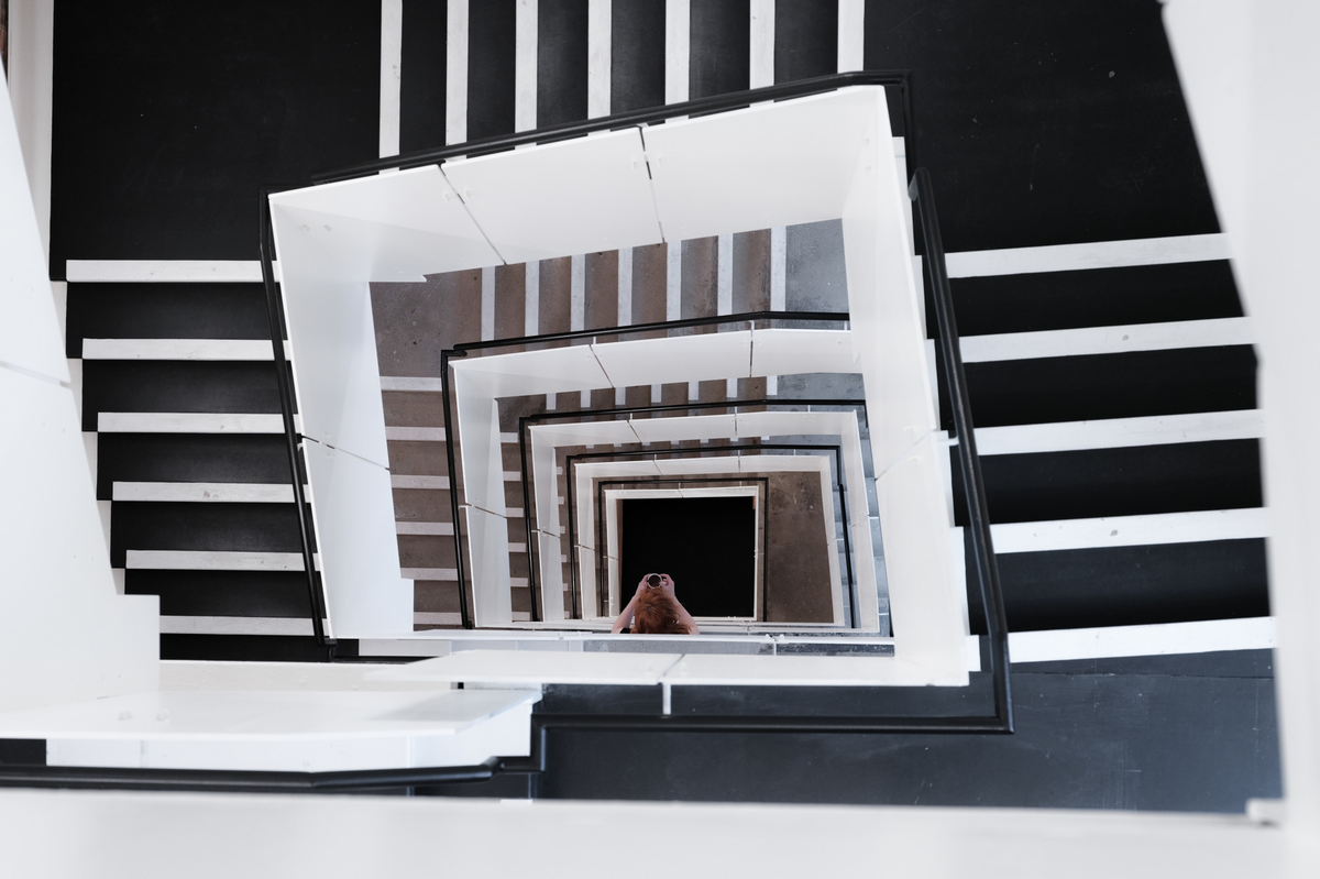 Blick von oben in ein schwarz-weißes Treppenhaus.