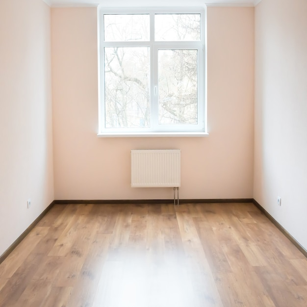 Leeres helles Zimmer mit Fenster und Holzboden.